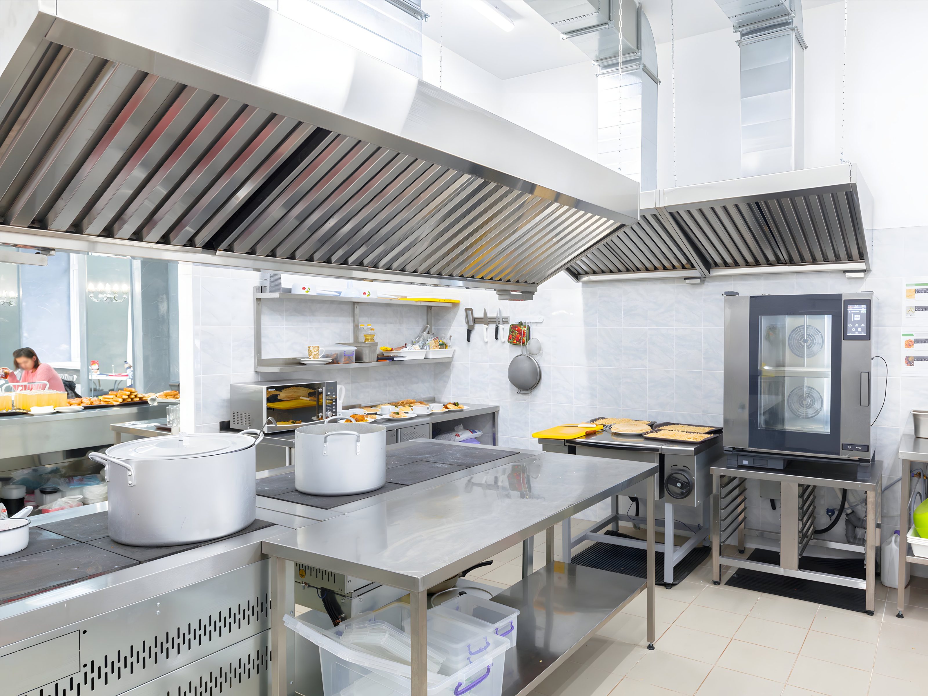 A commercial kitchen's long exhaust hood line over the cook line